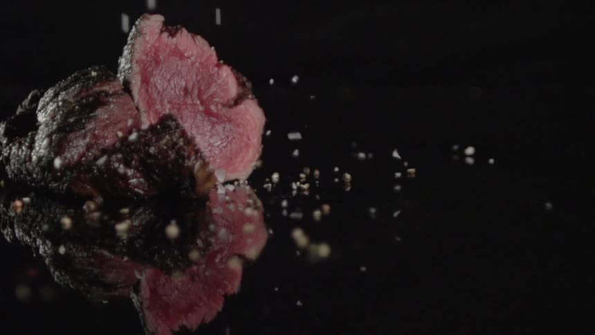 Seasoning is sprinkled on cooked steak