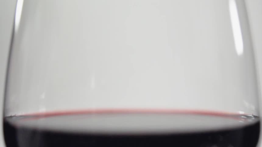 Red liquid droplets splash into a glass