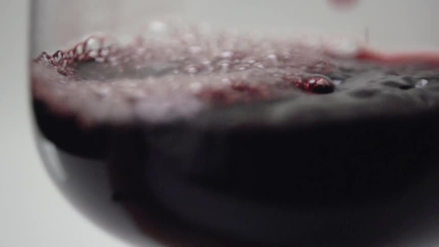 Red wine is poured into a glass