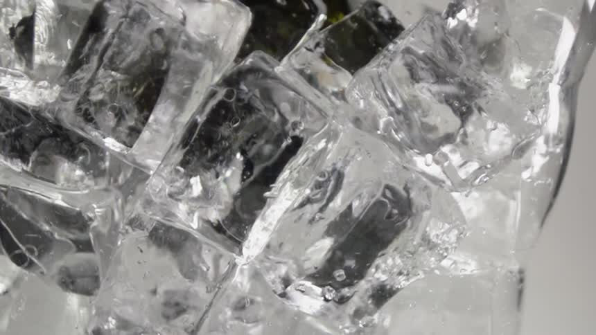 Ice cubes fall into a glass