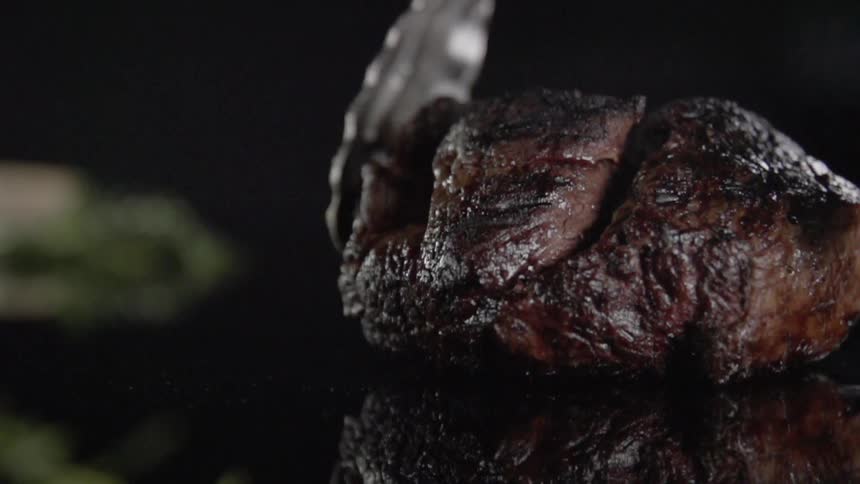 A piece of cooked meat is dropped using tongs