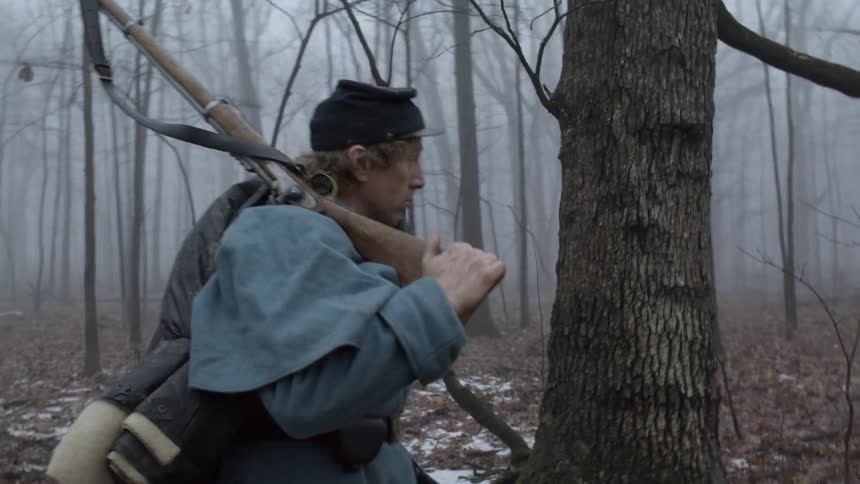 A soldier carries his rifle through the woods