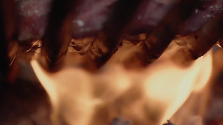 Meat cooks on a grill over the flames