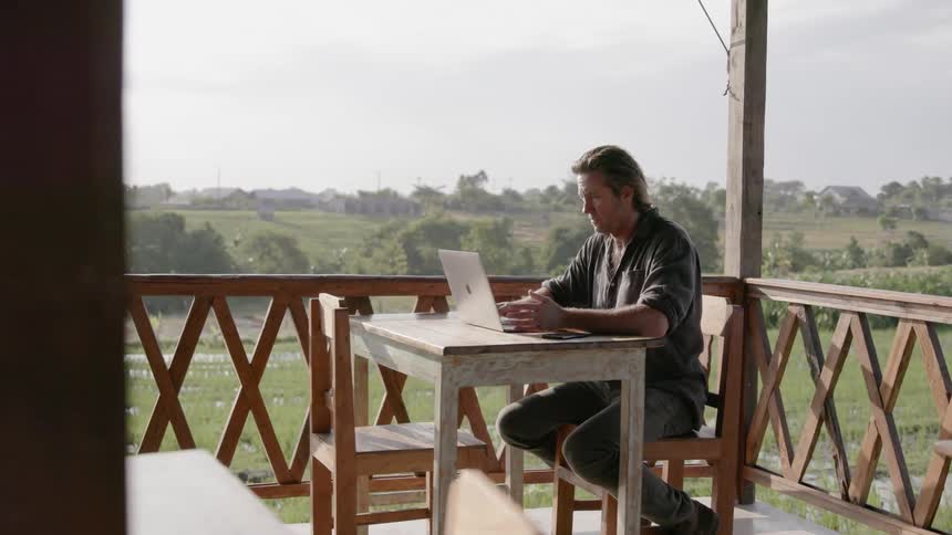 Man works on a laptop on a patio