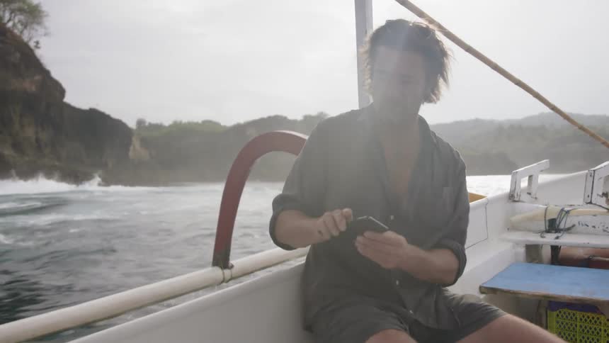 Man sits on a boat as it travels through the water