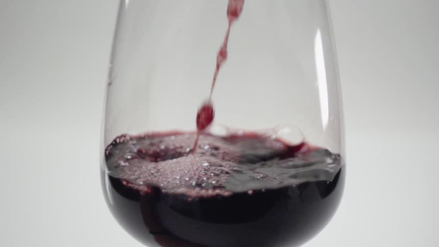 Wine pours into a clear wine glass