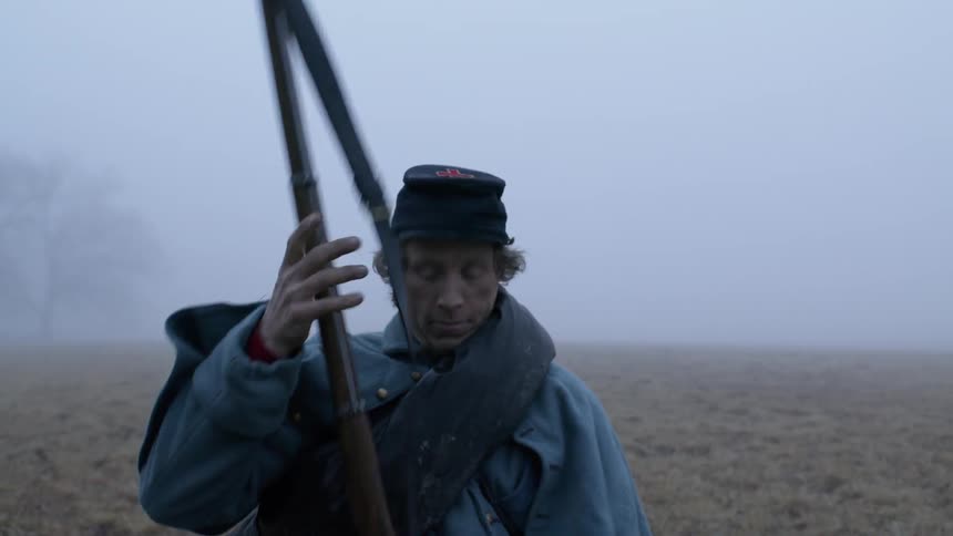 A solder carries a rifle in a foggy field