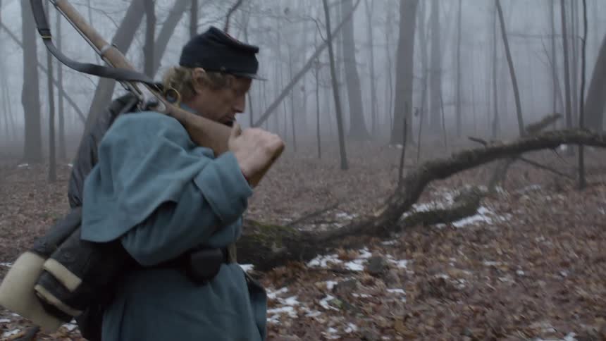 A soldier carries his rifle through the woods
