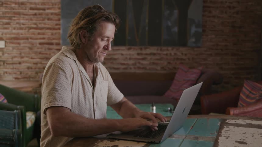 A man begins to type on a laptop after thinking
