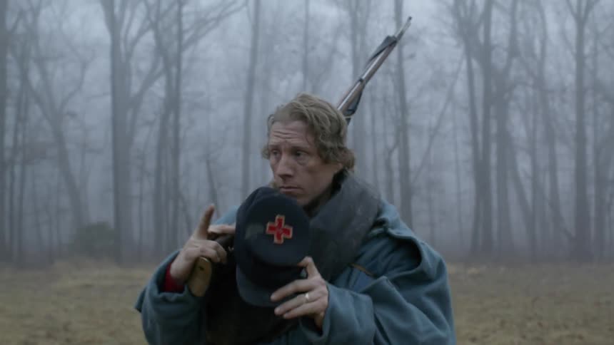 A soldier carries his rifle through the woods
