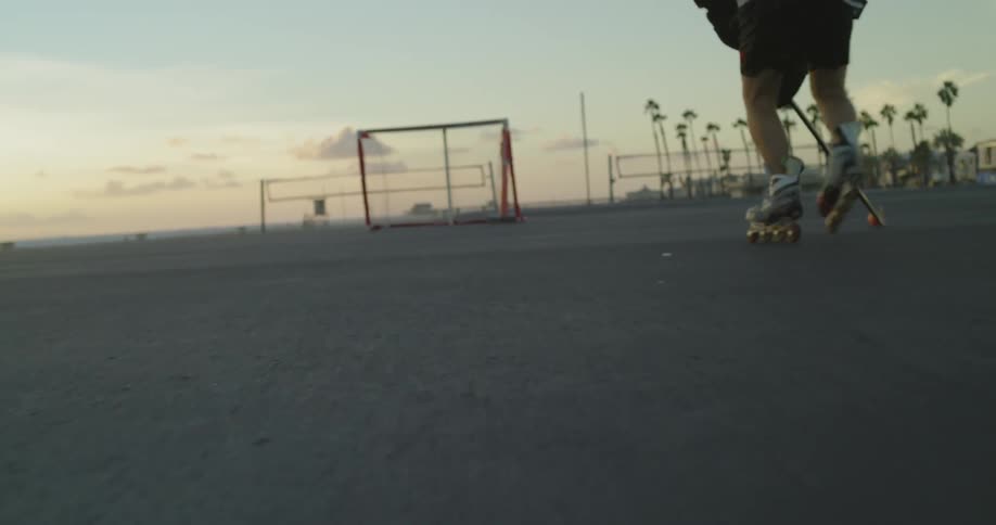 A man plays roller hockey on a beach at sunset