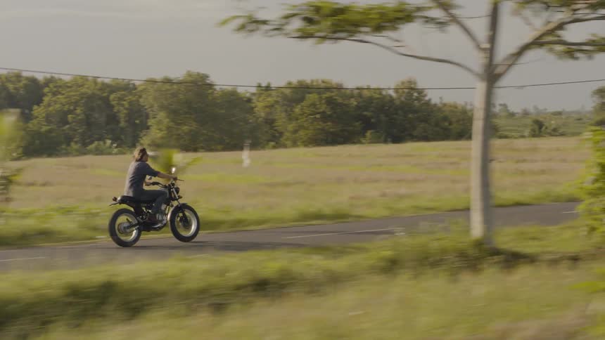 A person is riding their motorcycle on the small road
