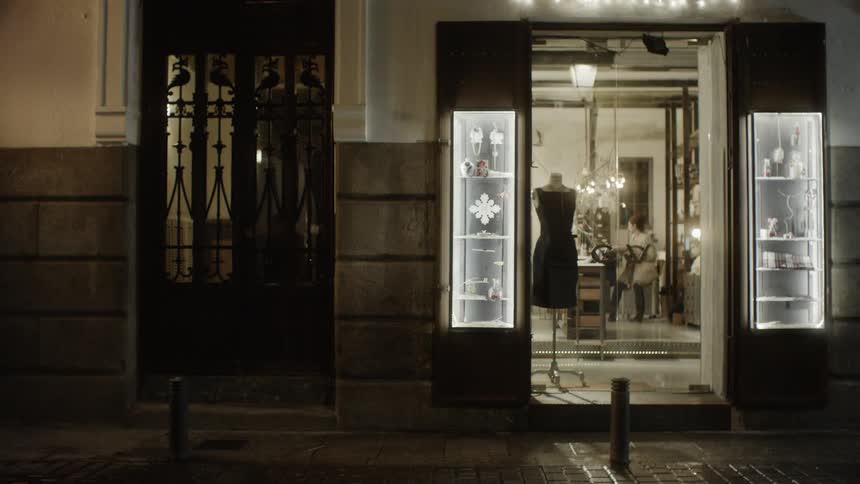 A dress form with a dress stands in the open doorway of a shop at night