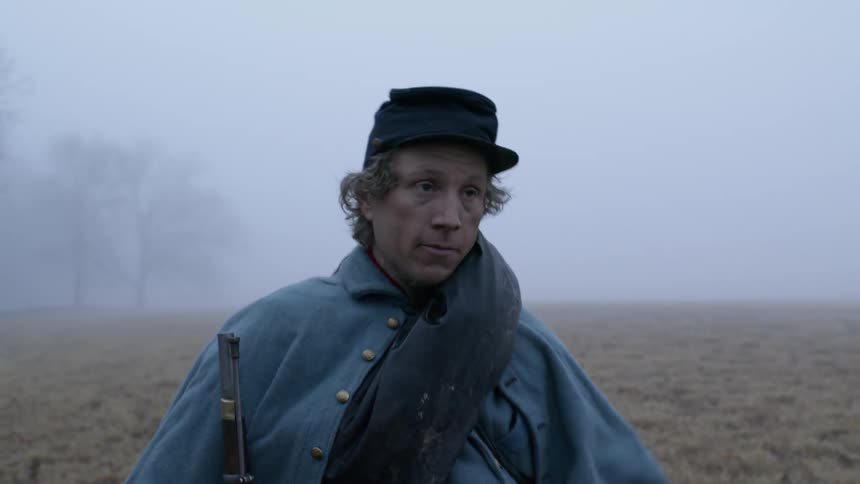 Man carries a gun in a field on a foggy day