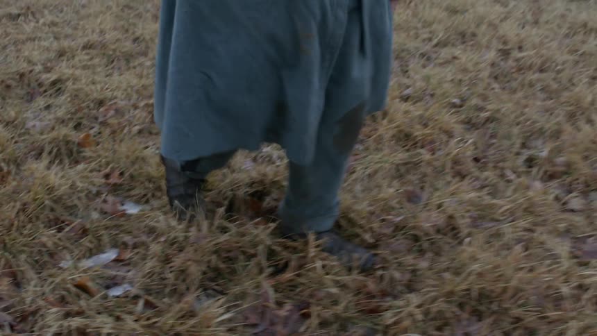 The man carries his rifle as he walks over the field