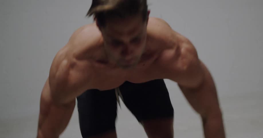 Shirtless man jumps and exercises indoors