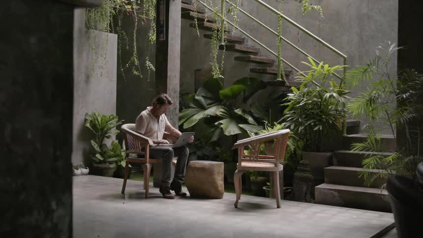 Man sits in a chair as he types on a laptop