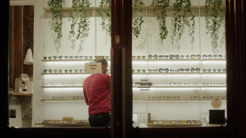Man looks at glasses on a store shelf