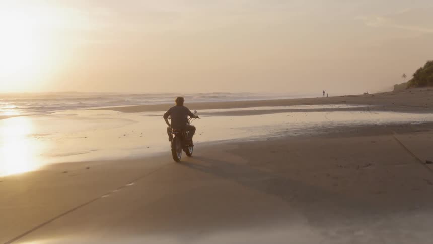A person rides their dirt bike on the beach