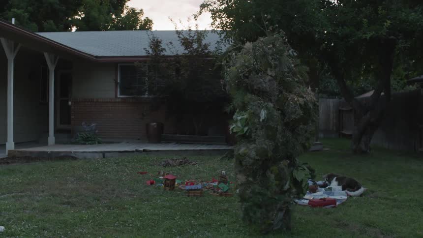 The person wearing camouflage walks towards the house