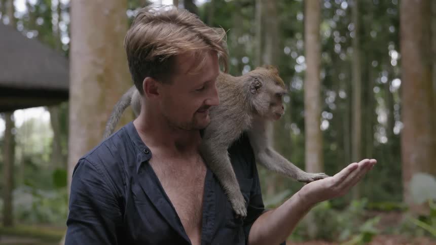 Man smiles with a monkey on his shoulder