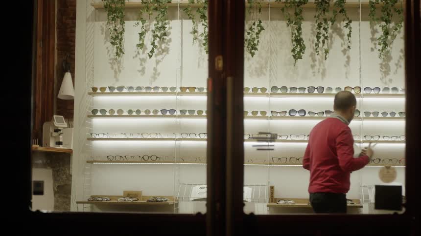 Man looks at glasses on a store shelf