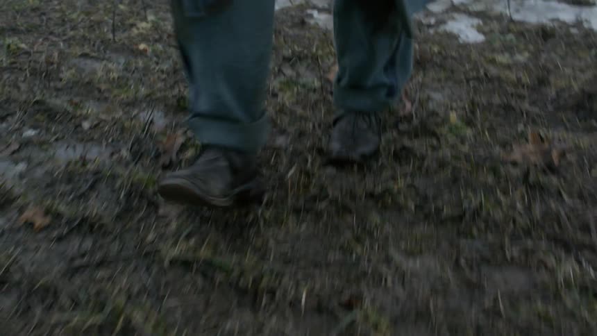 A man walks on an icy and muddy field