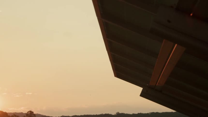 The sun sets behind a solar panel