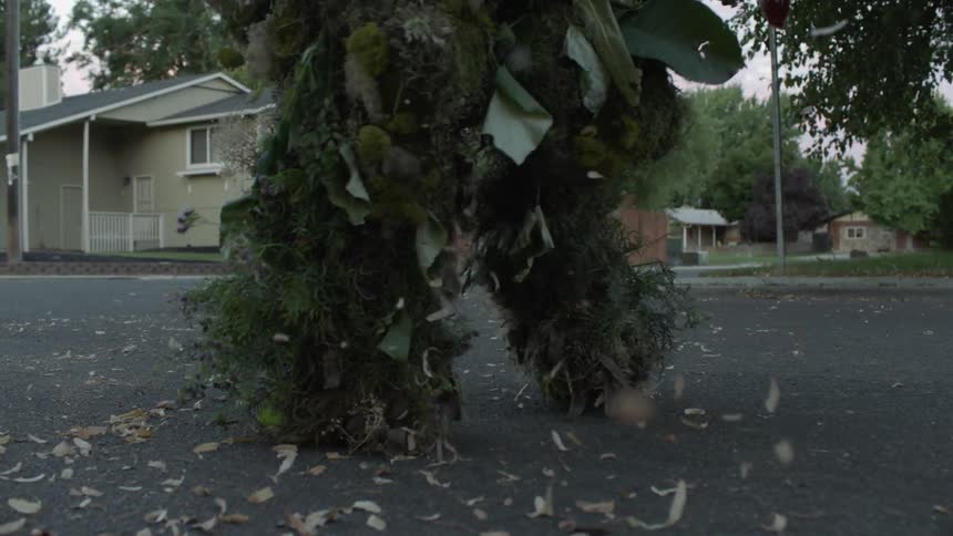 A plant creature sheds while walking on a street