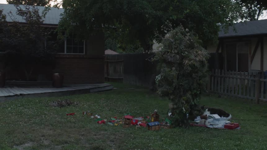 A person wearing leaves all over walks over debris in the yard
