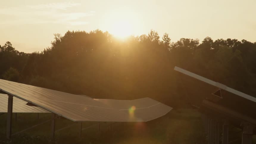 The sun is setting behind the solar panels
