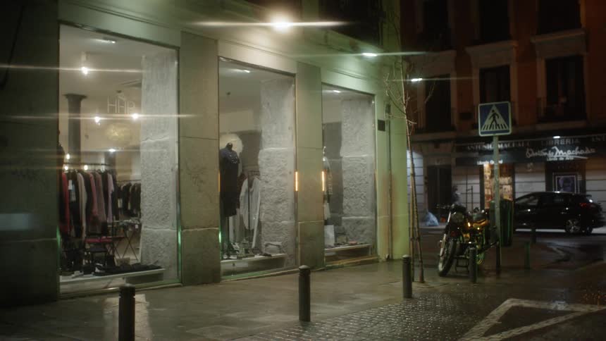 Clothing hands in a store as pedestrians walk down the sidewalk