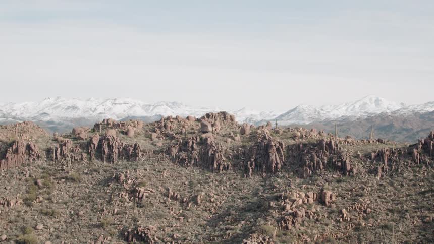 Rocky dirt covered landscape with snow capped mountains behind