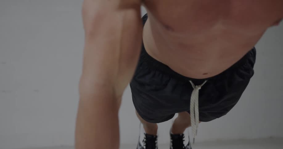 A man is doing pushups wearing black shorts