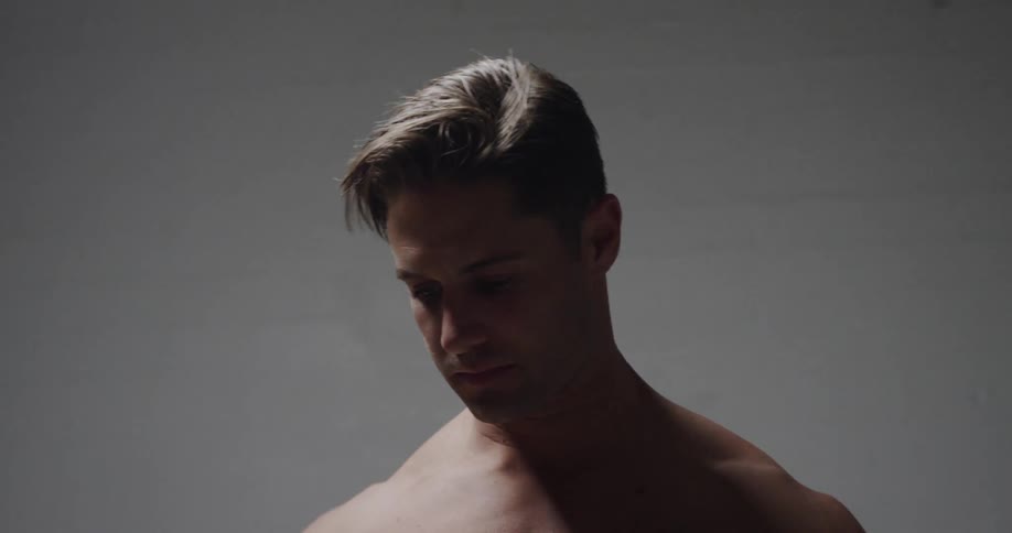 Muscular man takes off his shirt