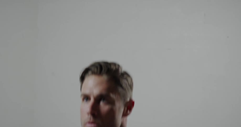 Man does crouches with his hands clasped to his chest