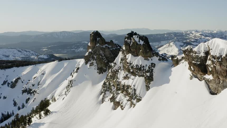 Flying towards a snowy mountain range in the winter at sunrise