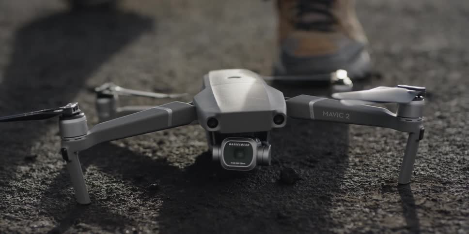 A man places a drone on the ground on a sunny day