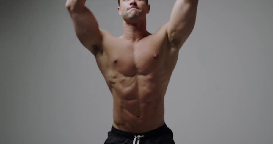 A shirtless man jumps and exercises