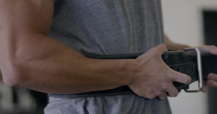 A man puts on a weight lifting belt