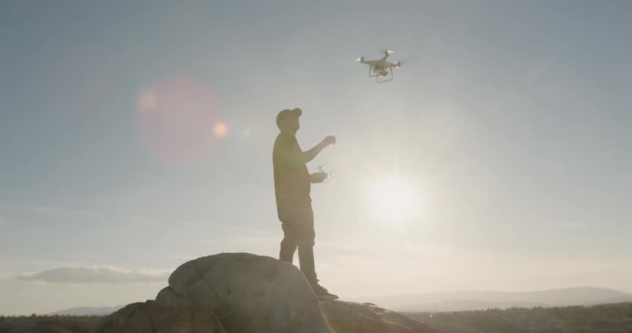 Man flies a drone on a mountain peak