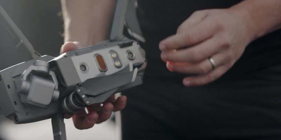 A man unfolds the legs of a drone