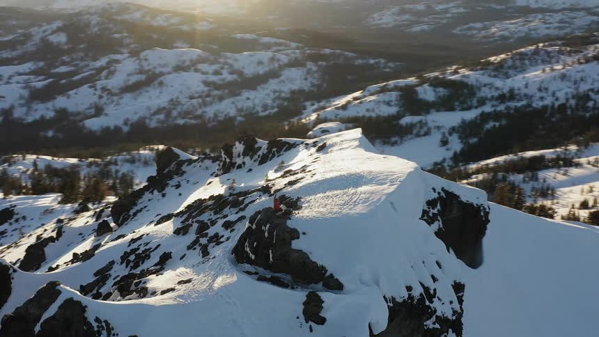 A hiker stands on a snowy mountain peak