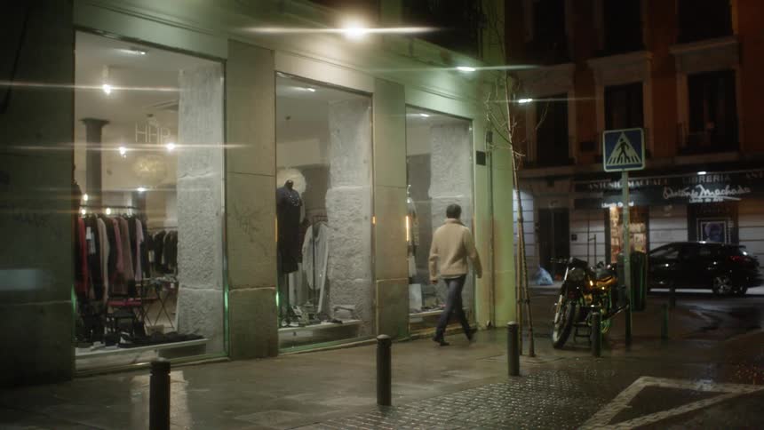 Man walks on a city sidewalk at night