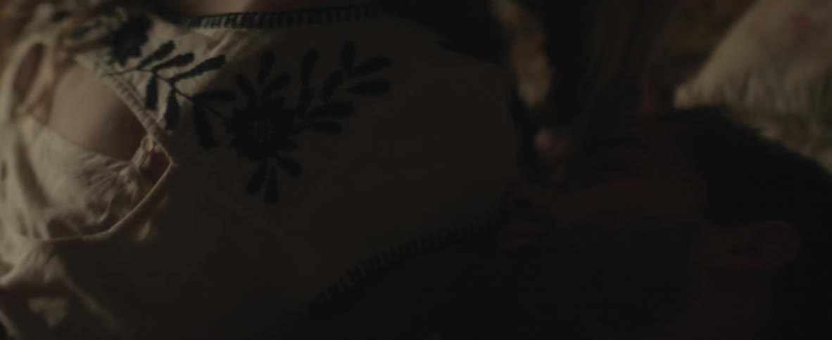 A man in a woman lay in bed together caressing one another