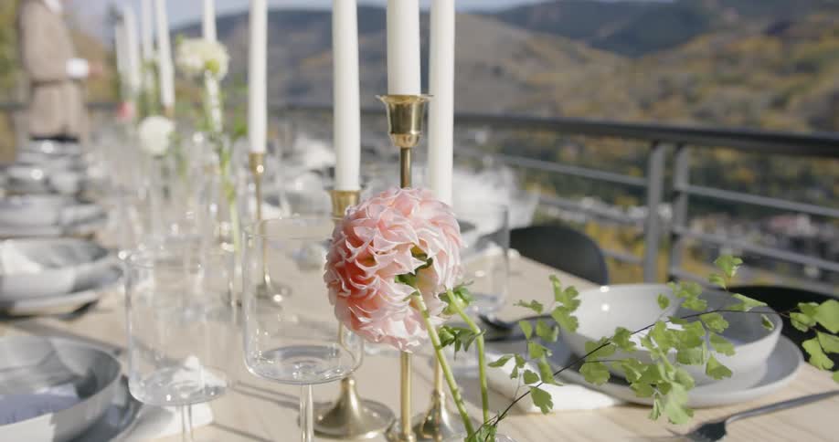 Flowers in a vase on a dinner table blow in the wind outside in daylight