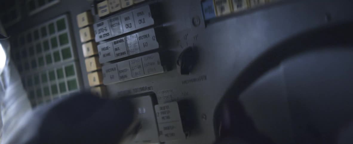 A gloved hand turning a switch on a control panel
