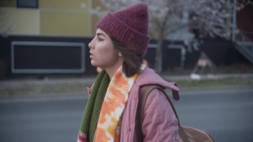 Woman with a backpack walks as traffic goes by