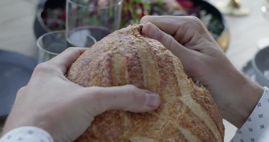 A person tears off a piece of bread at dinner