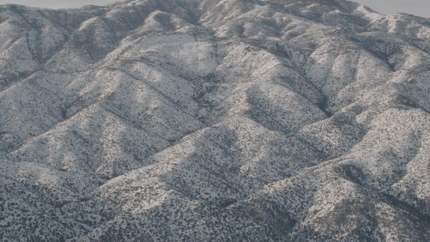 Snow and shrubs cover hills
